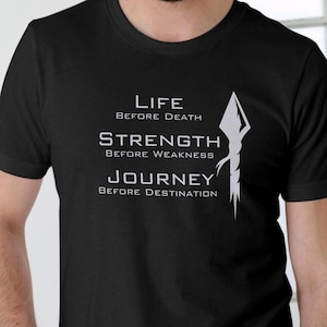 K&ouml;nnte beinhalten: Schwarzes T-Shirt mit einem wei&szlig;en Grafikdesign mit einer Lanze und dem Text "Life Before Death, Strength Before Weakness, Journey Before Destination."