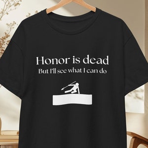 Puede incluir: Camiseta negra con texto blanco que dice "El honor está muerto Pero veré qué puedo hacer" y un gráfico de una persona sosteniendo una lanza.