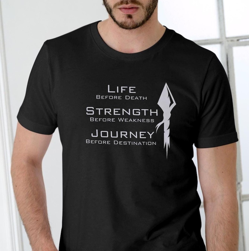 K&ouml;nnte beinhalten: Schwarzes T-Shirt mit einem wei&szlig;en Grafikdesign mit einer Lanze und dem Text "Life Before Death, Strength Before Weakness, Journey Before Destination."