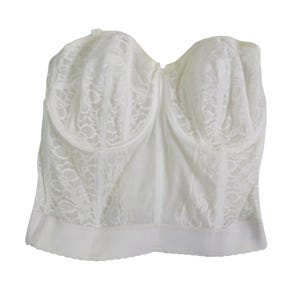 May include: Ivory-colored bustier with a sweetheart neckline. The garment features a delicate lace overlay on the cups and sides, with a smooth, opaque panel in the center. The bottom edge has a subtle, scalloped trim.