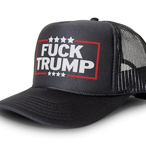 May include: Black trucker hat with a mesh back and a curved brim. The front panel displays the text "FUCK TRUMP" in white block letters inside a red-lined rectangle, with stars above and below.