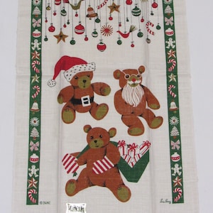 May include: A white tea towel with a green Christmas tree design. The tree is decorated with ornaments, candy canes, and stars. Three brown teddy bears are featured, one wearing a Santa hat, one with a beard, and one holding a box of presents. The text "Lila Perry" is printed in the bottom right corner.