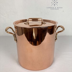 May include: A polished copper stockpot with two side handles and a matching lid. The pot features a cylindrical body and a flat lid with a central handle. The logo for Copper & Wood Vintage is visible in the upper right corner of the image.