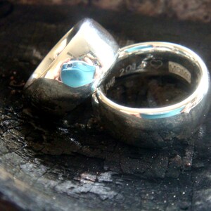 May include: Two silver wedding bands, one with a heart and the inscription "2014" and the other with a smooth surface.