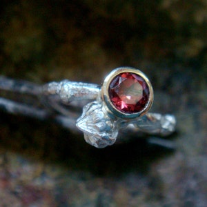 May include: A silver ring with a textured band and a single red gemstone set in a silver bezel.