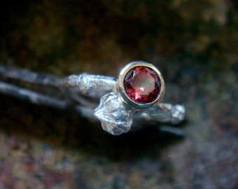 May include: A silver ring with a textured band and a single red gemstone set in a silver bezel.