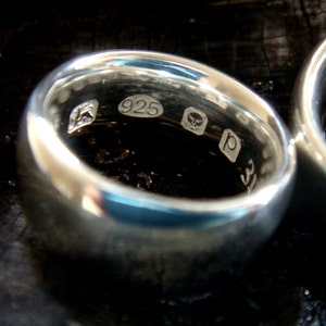 May include: Close-up of a silver ring with the inscription "925" and other markings.