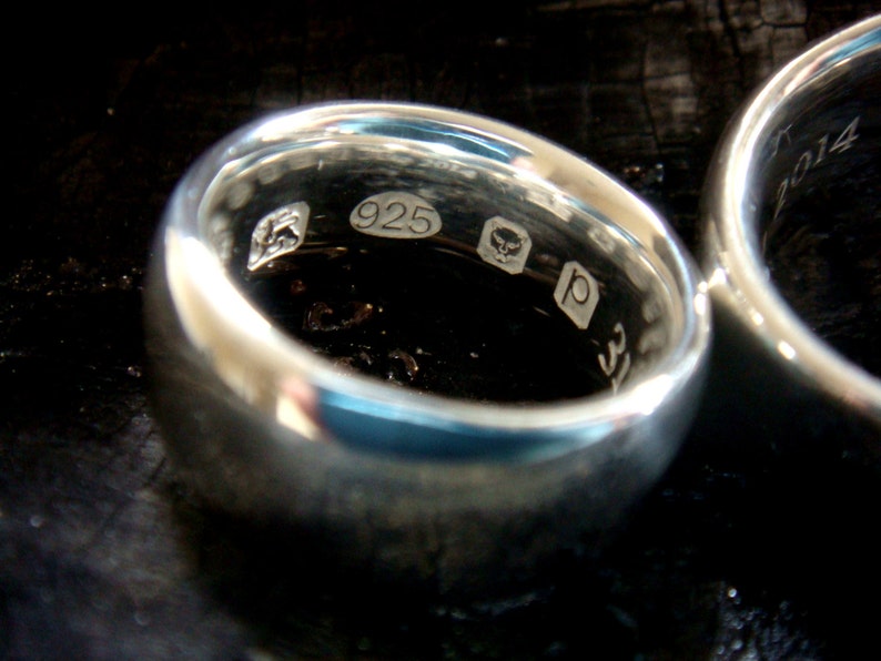 May include: Close-up of a silver ring with the inscription "925" and other markings.