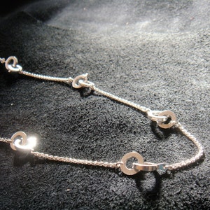 May include: A silver necklace with a delicate chain and multiple linked heart-shaped pendants.