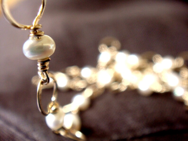 May include: A gold chain necklace with white pearl beads. The necklace is made of wire and has a simple design.