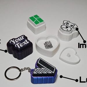 Peut inclure: Un ensemble de composants de touches de clavier mécanique imprimés en 3D, incluant une pièce violet foncé avec le texte Your Text, une pièce blanche avec un dessin de chien, un contenant blanc en forme de cœur et un porte-clés bleu avec un logo noir.