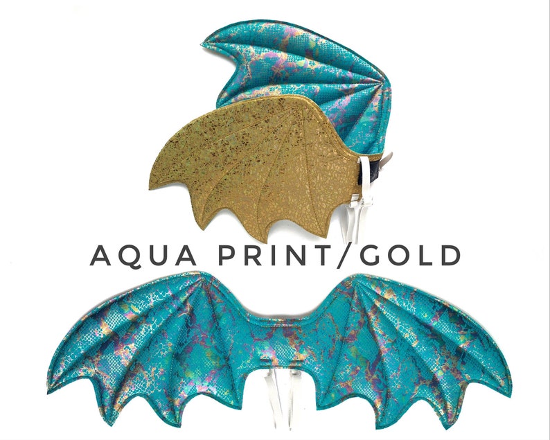 May include: A pair of dragon wings, one set is gold with a glitter finish, the other is a teal blue with a shimmery finish. The wings are labeled "Aqua Print/Gold".