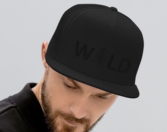 May include: Black trucker hat with the word "WILD" embroidered on the front. The hat features a mesh back and a flat brim. The text includes a tree graphic. The hat is worn by a person wearing a black jacket.