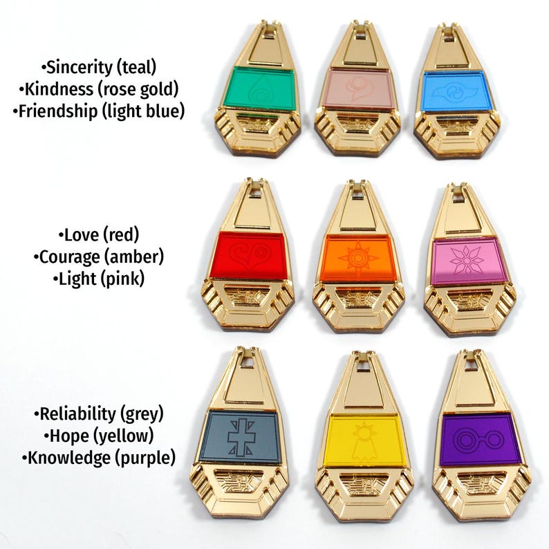 May include: Nine gold-colored charms with different colored glass inserts. Each charm has a different symbol and text describing the meaning of the charm. The text includes: Sincerity (teal), Kindness (rose gold), Friendship (light blue), Love (red), Courage (amber), Light (pink), Reliability (grey), Hope (yellow), and Knowledge (purple).
