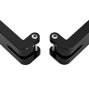 May include: Two black, L-shaped metal objects with rounded edges and a screw on the top. Each has a cylindrical pin extending from the bottom. The objects are set against a white background.