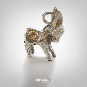 Pode incluir: Um amuleto de prata em forma de burro. O amuleto é detalhado e tem um laço para prender a uma pulseira ou colar.