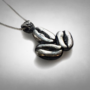 Peut inclure: Un collier en argent avec un pendentif en forme de trois grains de café.