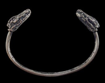 May include: A silver bracelet with two alligator head ends.