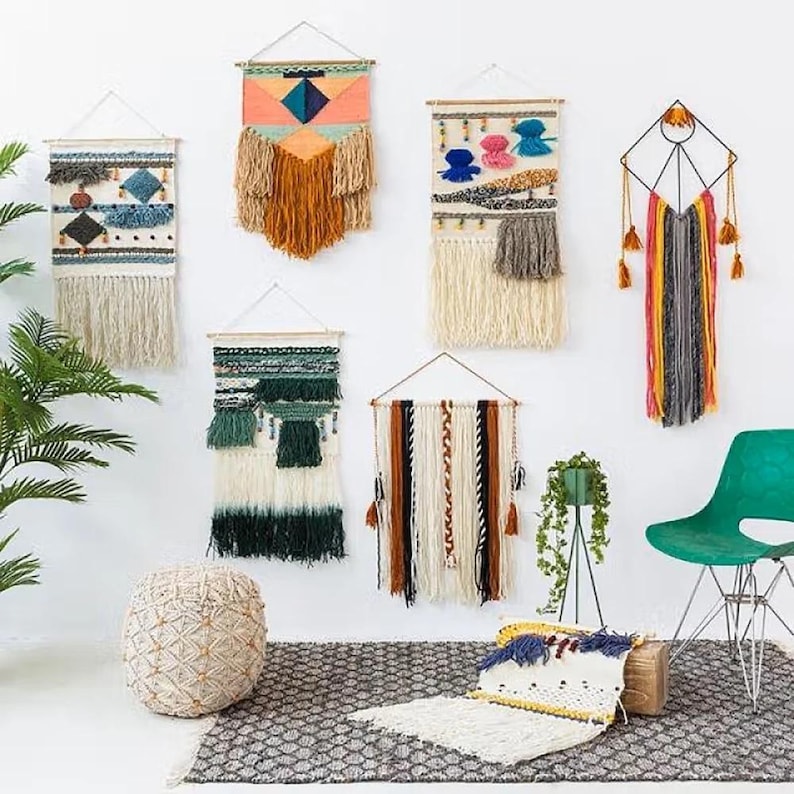 K&ouml;nnte beinhalten: Eine Sammlung handgefertigter Wandbeh&auml;nge in verschiedenen Gr&ouml;&szlig;en und Designs. Die Textilkunstwerke weisen eine Mischung aus Farben, Texturen und Mustern auf, darunter Fransen, geometrische Formen und gewebte Details. Die Dekoration wird an einer wei&szlig;en Wand pr&auml;sentiert.