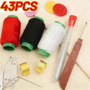 May include: A 43-piece sewing kit featuring three spools of thread in red, black, and white, two gold-colored metal thimbles, a clear plastic needle case, a brown seam ripper, two flat metal needle threaders, and two round plastic buttons.