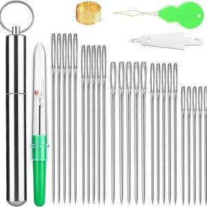 May include: A sewing kit with various tools. Includes a silver needle case, a needle threader, a seam ripper, a thimble, and multiple sewing needles of different sizes. The tools are arranged on a white background.
