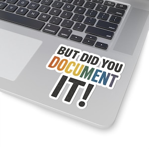 May include: A white sticker with the text "BUT DID YOU DOCUMENT IT!" in black, orange, yellow, green, blue, and purple. The sticker is on a silver laptop.