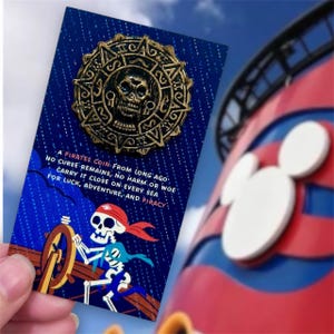 May include: A gold-colored pirate coin pin with a skull design, mounted on a blue card with text. The card features a skeleton pirate illustration and the text: "A Pirates Coin From Long Ago...For Luck, Adventure, and Piracy."