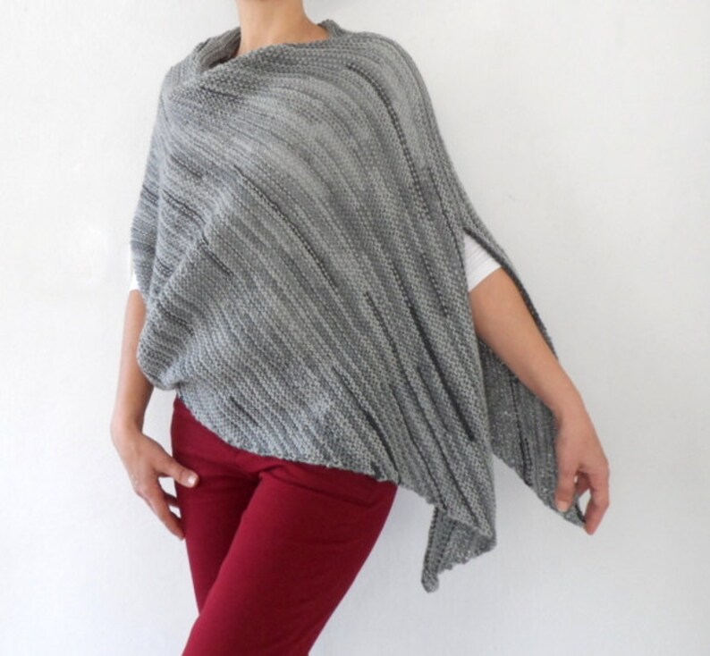 Pu&ograve; includere: Un poncho di maglia grigia con una vestibilit&agrave; ampia e drappeggiata. Il poncho ha un'ampia scollatura e un orlo leggermente asimmetrico.