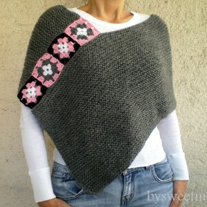 Puede incluir: Poncho de punto gris con ribete de ganchillo rosa y blanco. El ribete presenta una serie de dise&ntilde;os cuadrados con flores.