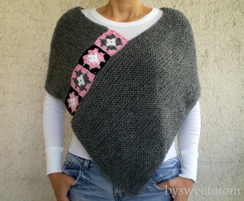 Puede incluir: Poncho de punto gris con una fila diagonal de cuadrados de ganchillo rosa y negro.
