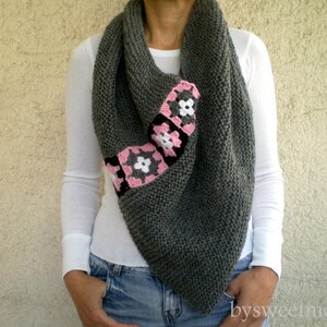 Puede incluir: Una bufanda de punto gris con un dise&ntilde;o de flores de ganchillo rosa y blanco.