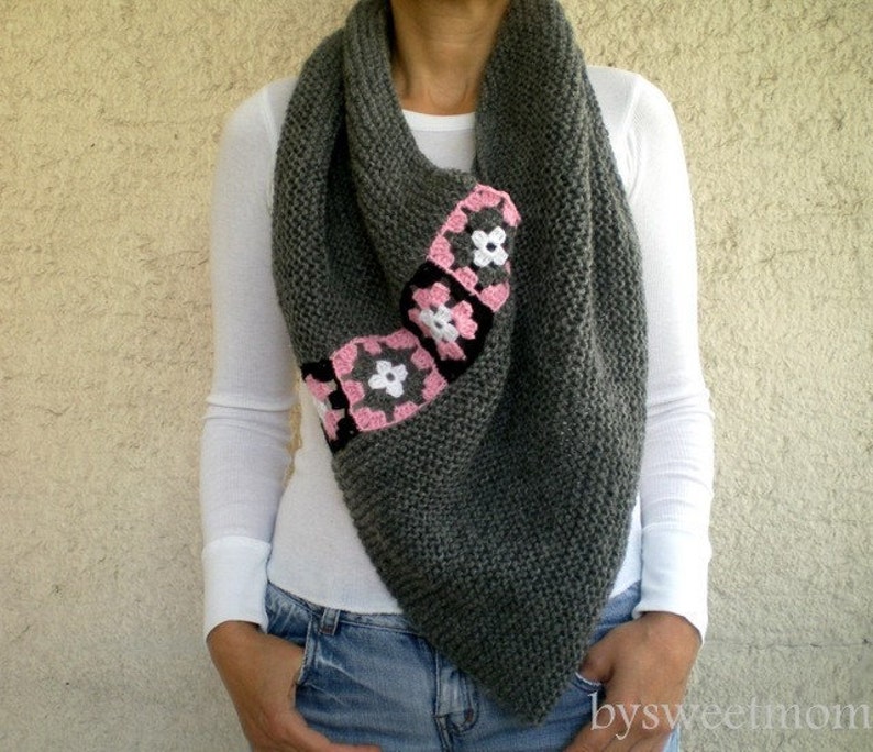 Puede incluir: Una bufanda de punto gris con un dise&ntilde;o de flores de ganchillo rosa y blanco.