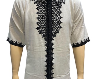 May include: Off-white caftan with black embroidery and trim. The short-sleeved garment features intricate geometric patterns around the neckline and down the front. The caftan is displayed on a mannequin. The text "AHMED ARTISANALS CAFTAN" is visible.