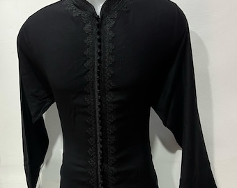 May include: Black long-sleeve caftan with intricate embroidery along the front and collar. The caftan has a mandarin collar and a full-length zipper. The brand name "AHMED ARTISANALS CAFTAN" is visible in the upper right corner.