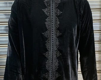 May include: Black velvet tunic with intricate embroidered detailing down the front and around the collar. The long-sleeved tunic has a mandarin collar and a full-length zipper. The garment is displayed on a mannequin.