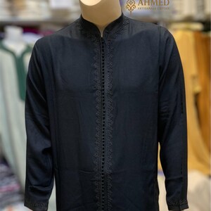 May include: Black caftan with intricate embroidery along the zipper and cuffs, displayed on a mannequin. The caftan has a mandarin collar and long sleeves. The text "AHMED ARTISANALS CAFTAN" is visible in the upper right corner.