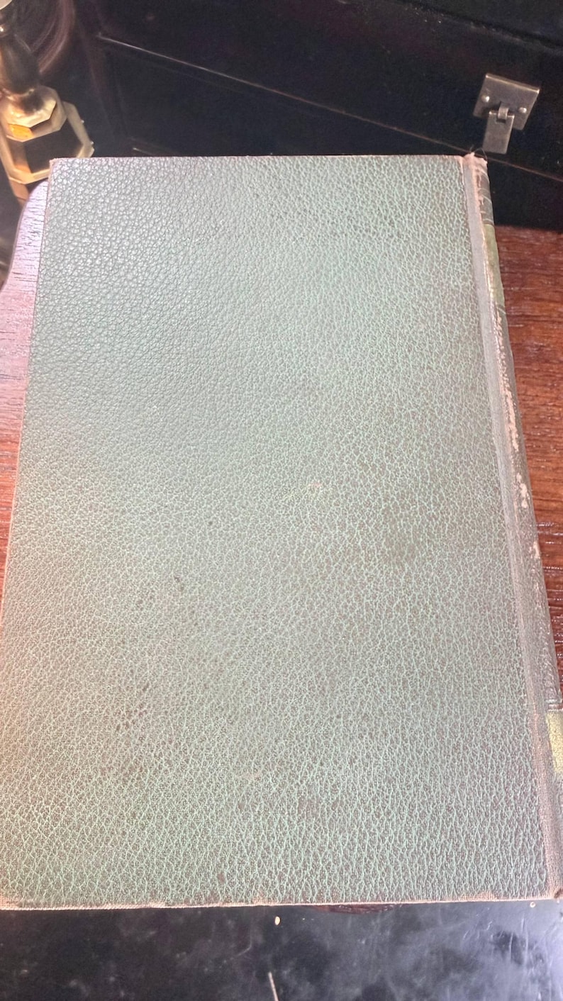 May include: A vintage book with a textured, pale green cover. The cover has a subtle, mottled pattern and a slightly worn appearance. The book's spine is visible, showing the binding and edges.