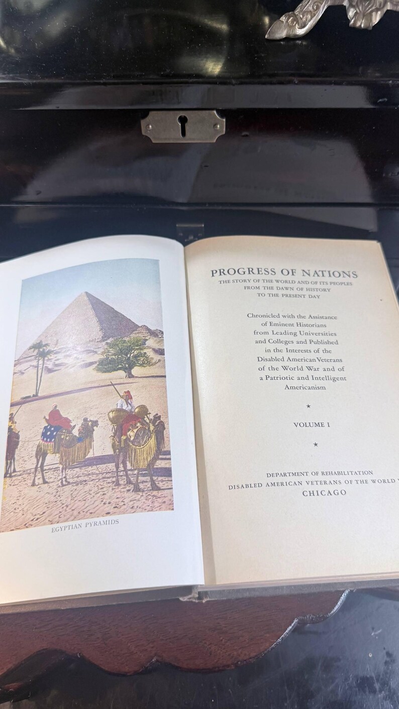 May include: An open book featuring a colour illustration of the Egyptian pyramids and camels. The text reads "Progress of Nations" and "Egyptian Pyramids". The book is Volume 1, published by the Department of Rehabilitation, Disabled American Veterans of the World, Chicago.