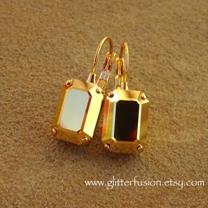 May include: A pair of gold-toned earrings with rectangular, emerald-cut crystals. The crystals reflect light, creating a shimmering effect. The earrings have a lever-back closure. The website address www.glitterfusion.etsy.com is visible at the bottom.
