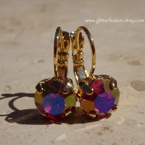 May include: A pair of gold hoop earrings with a red iridescent gemstone in the center of each hoop.