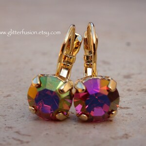 May include: A pair of gold earrings with iridescent purple and green gemstones. The earrings have a lever back closure.