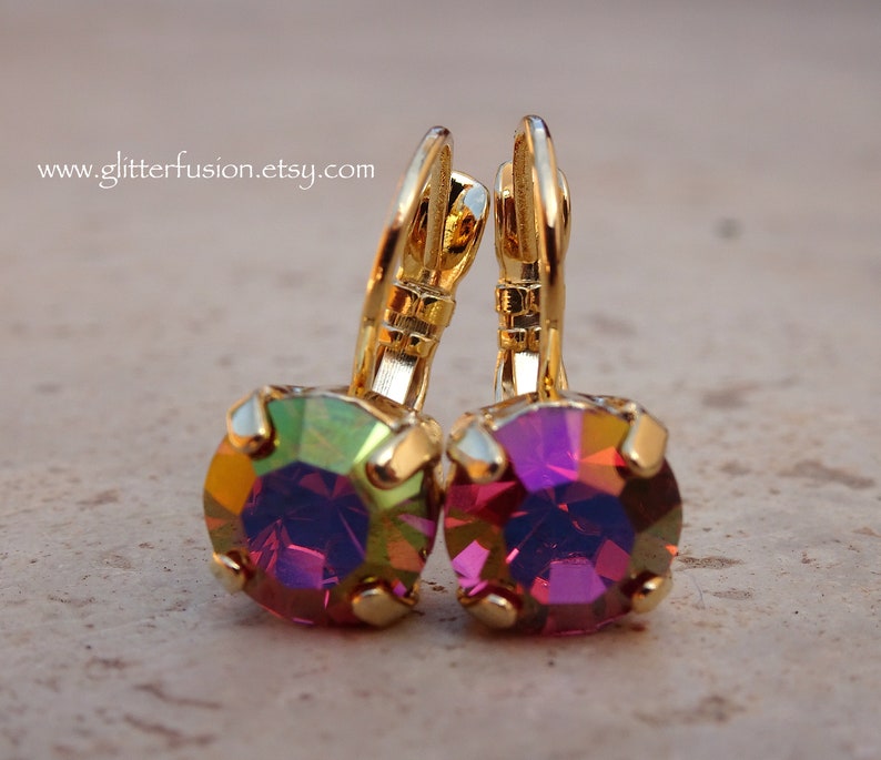 May include: A pair of gold earrings with iridescent purple and green gemstones. The earrings have a lever back closure.