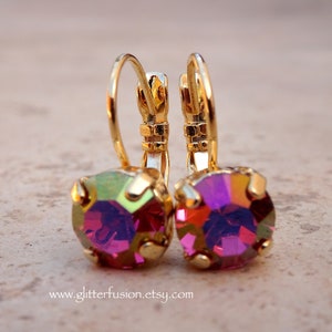 May include: A pair of gold hoop earrings with a pink iridescent gemstone in the center of each hoop.