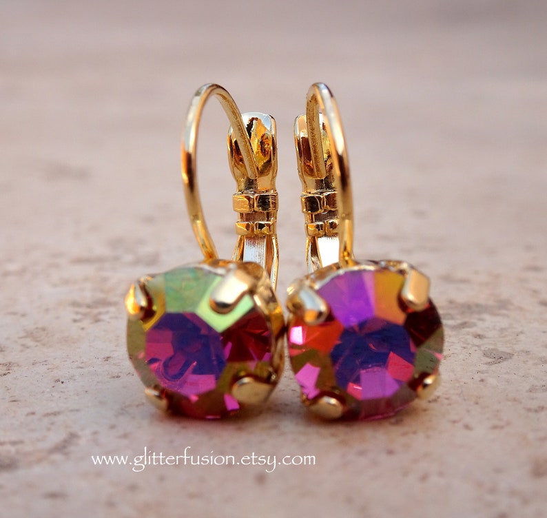 May include: A pair of gold hoop earrings with a pink iridescent gemstone in the center of each hoop.