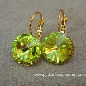 May include: A pair of leverback earrings featuring large, round, faceted, lime green crystals set in gold-tone metal. The earrings have a bright, sparkling appearance, reflecting light. The website address www.glitterfusion.etsy.com is visible at the bottom.