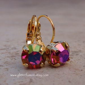 May include: Gold earrings with a pink iridescent gemstone. The earrings have a lever back closure.