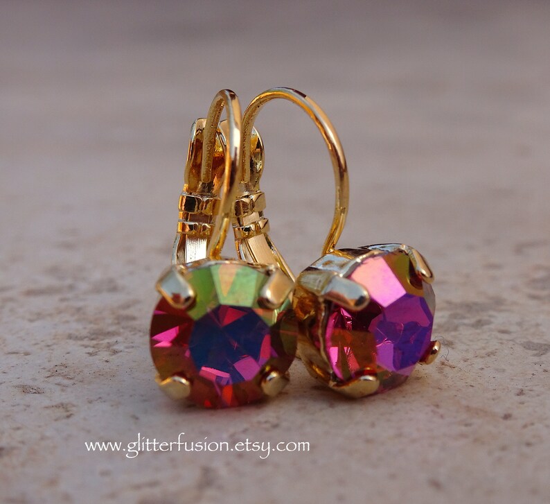 May include: Gold earrings with a pink iridescent gemstone. The earrings have a lever back closure.