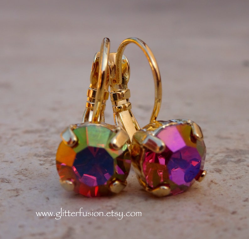 May include: A pair of gold earrings with iridescent pink and green gemstones. The earrings have a lever back closure.