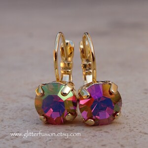 May include: A pair of gold hoop earrings with iridescent pink and purple gemstones. The earrings are small and delicate.