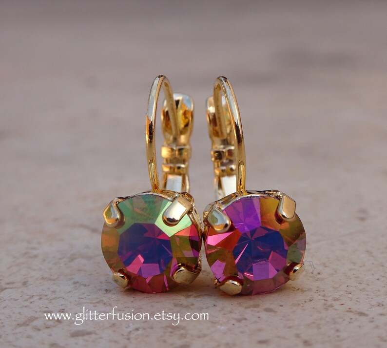 May include: A pair of gold hoop earrings with iridescent pink and purple gemstones. The earrings are small and delicate.